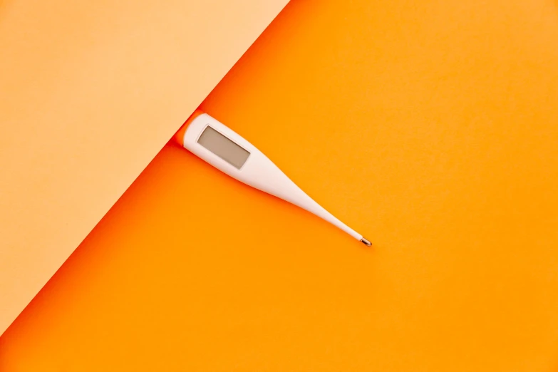 thermometer sits on top of an orange sheet of paper