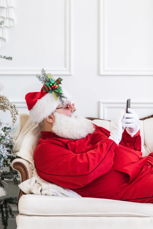 man in santa clause sitting on a couch with cellphone