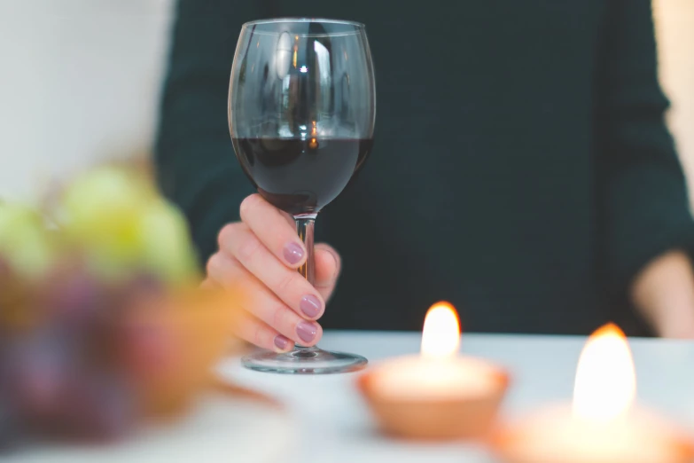 person with pink nail polish holding wine glass