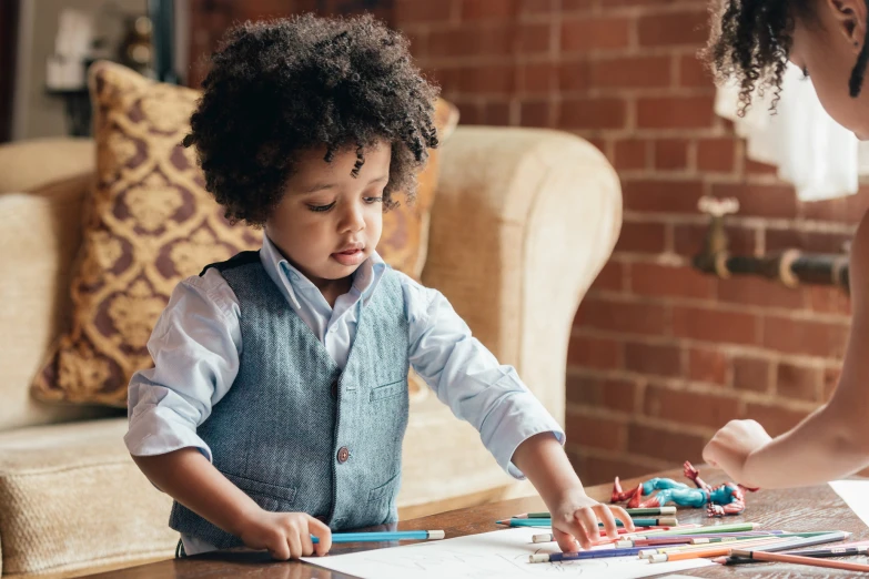 a young child standing at a table in front of a lady