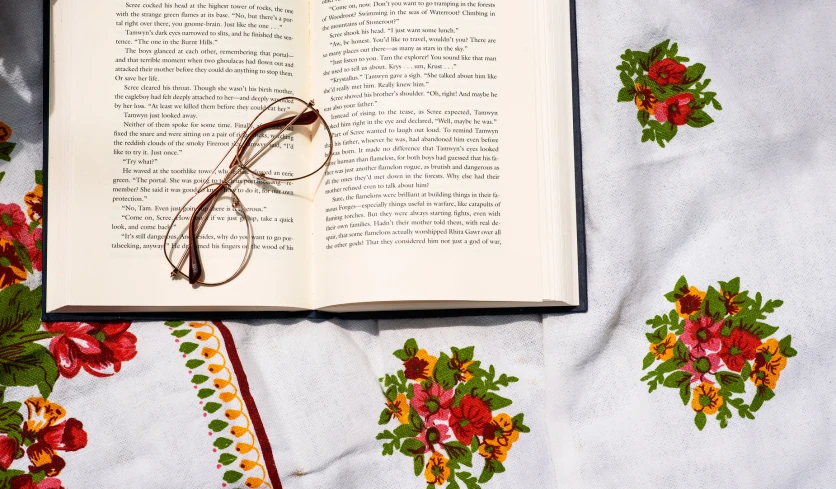 an open book on a floral table cloth