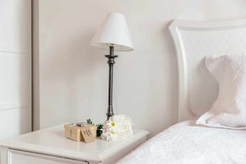 a white nightstand sitting next to a bed