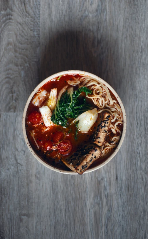 a bowl with noodle and meat soup sitting on a wooden table