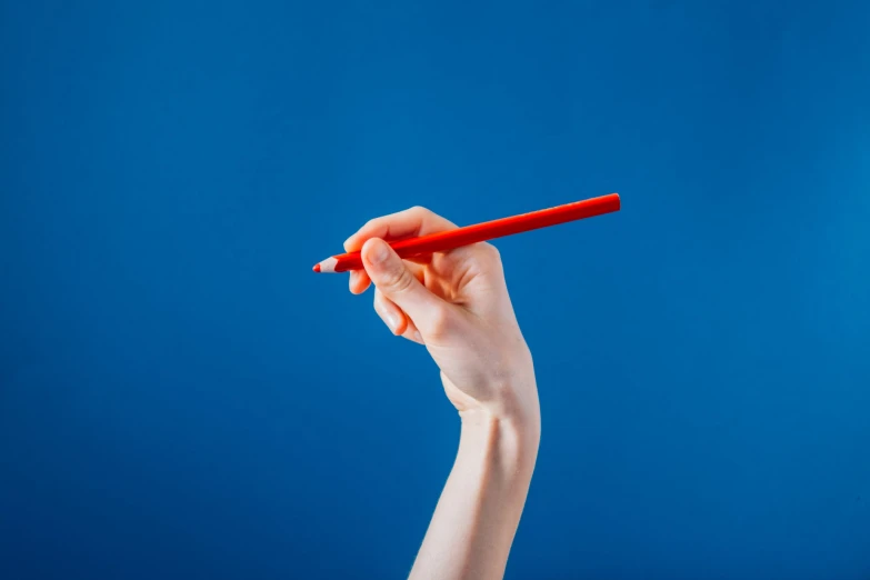 the hand holding a red pen is over blue