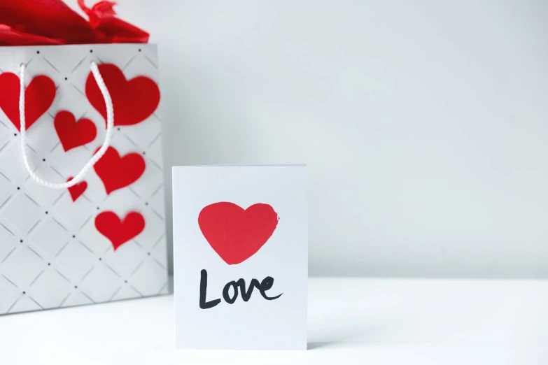 a card with a love tag on the front, and a small bag that has a large heart on it