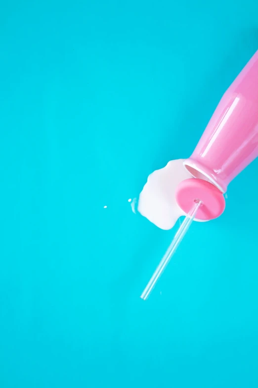 a pink liquid bottle with a toothbrush sitting on a blue surface