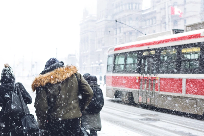 a group of people in the snow, waiting for a bus