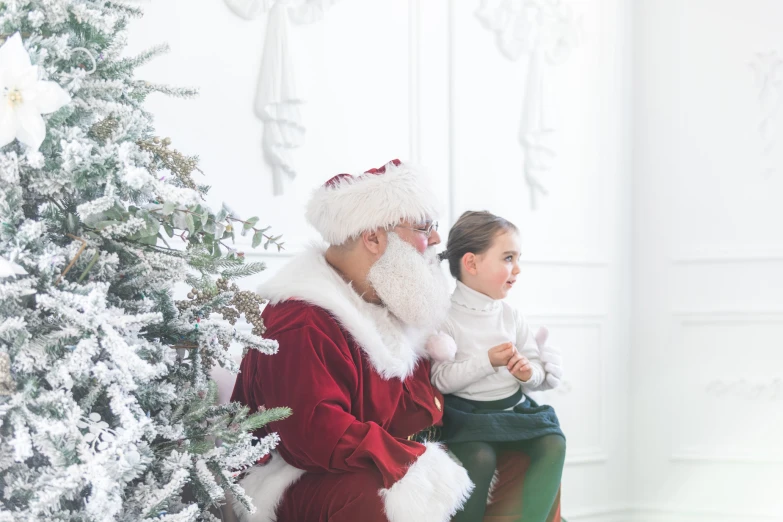 a woman sitting on top of a child in front of a christmas tree