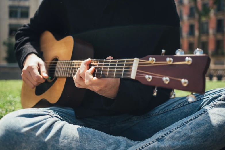 man with black shirt playing guitar in green grass