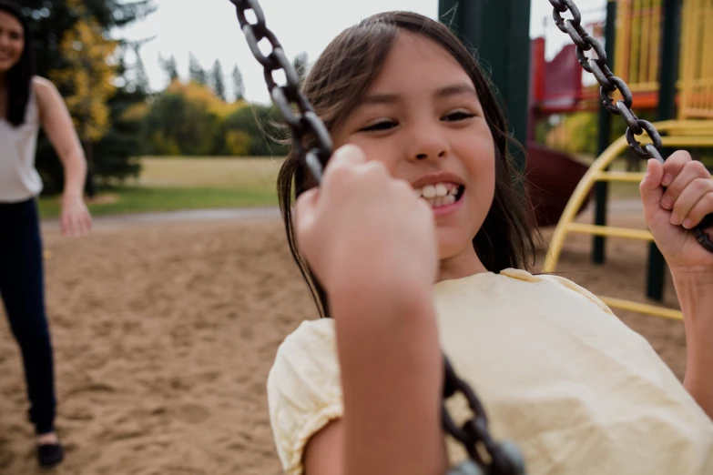 a smiling girl on a playground swing and a woman