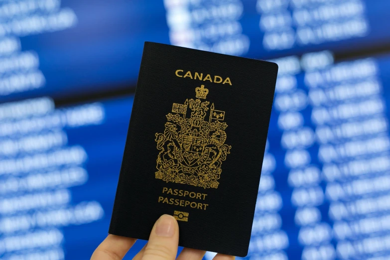 a hand is holding an canadian visa against a backdrop of blue screens