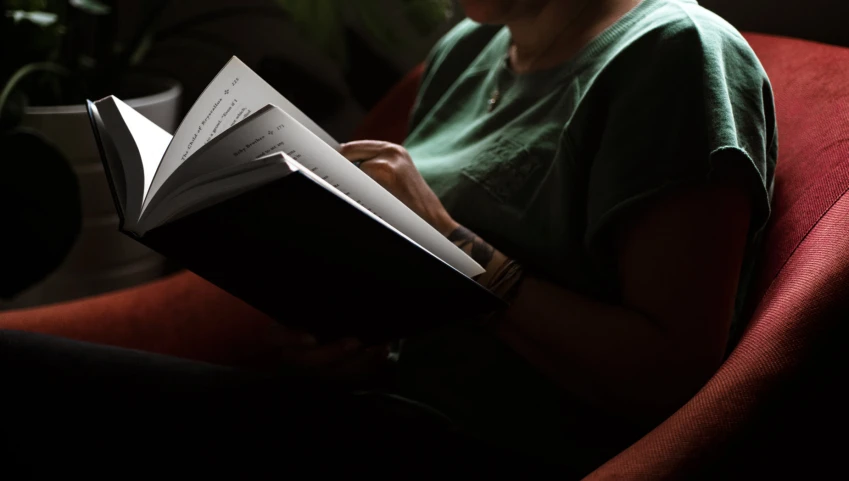 a woman sits in a chair reading a book