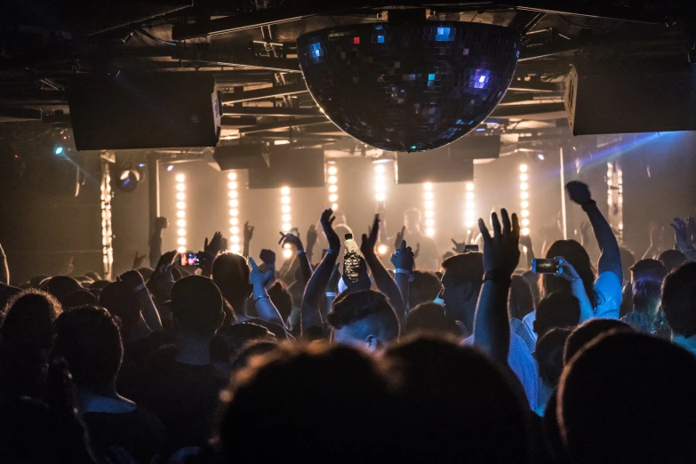 a crowd of people at a concert with their hands in the air