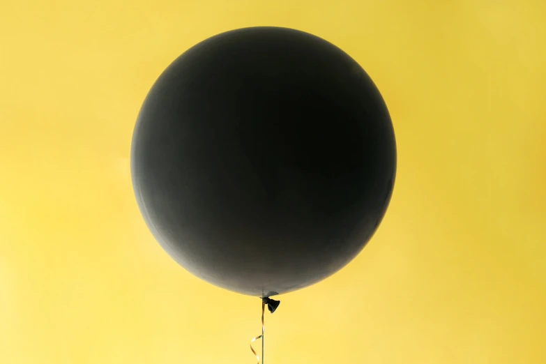 a black balloon is flying through the air