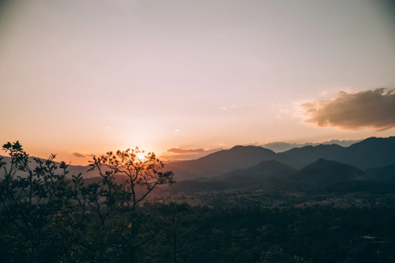 the sun is setting over some trees and mountains