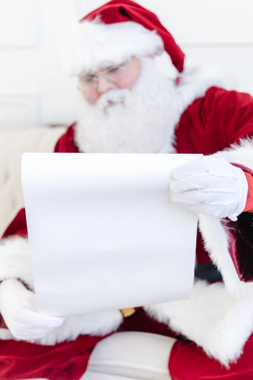 a man in santa suit sitting on a bench with his hands over a paper