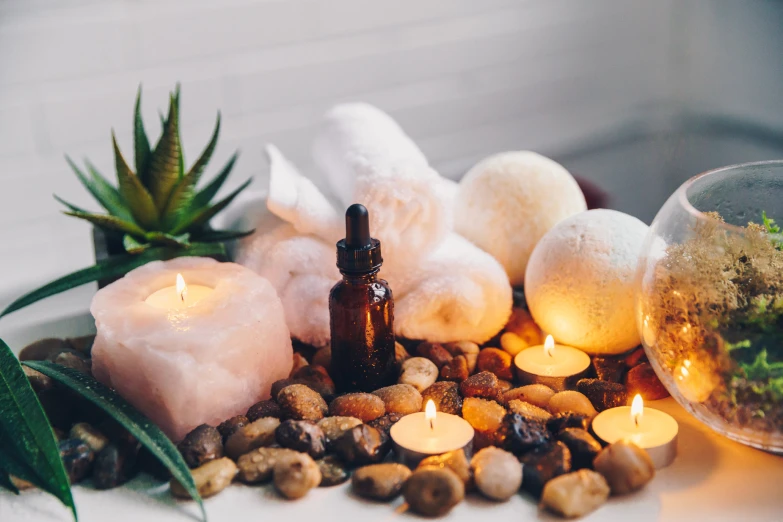 bottles are surrounded by pebbles and candles