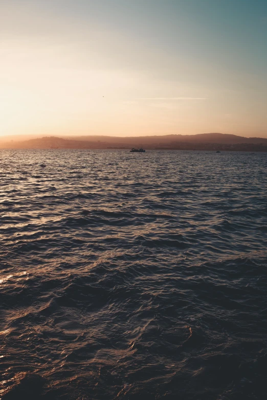 a distant view of a boat at sea as the sun is setting