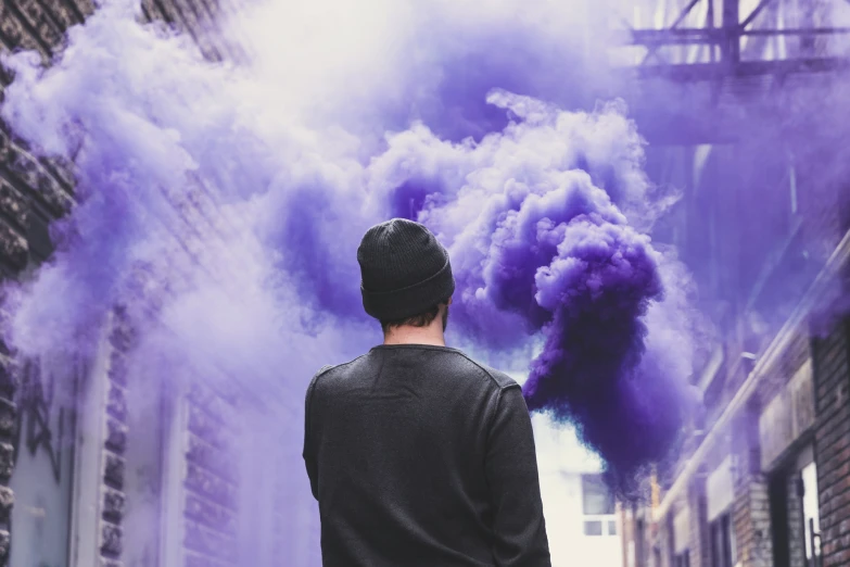 a man in black shirt standing next to building and smoke