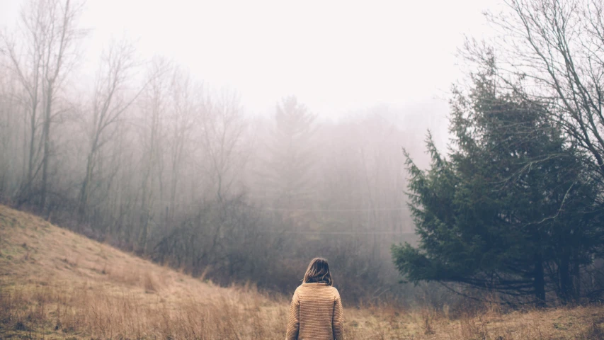 a woman walking through a field of tall grass