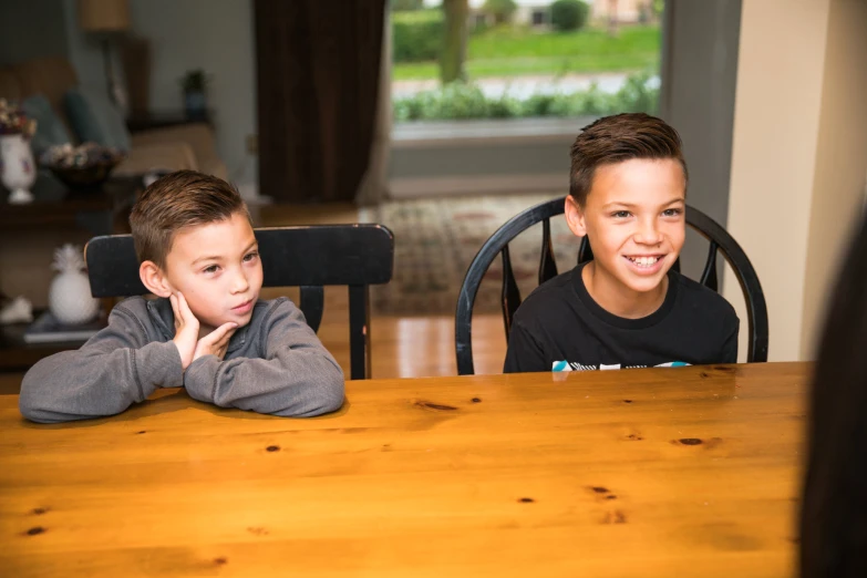 two young children are sitting at a table together