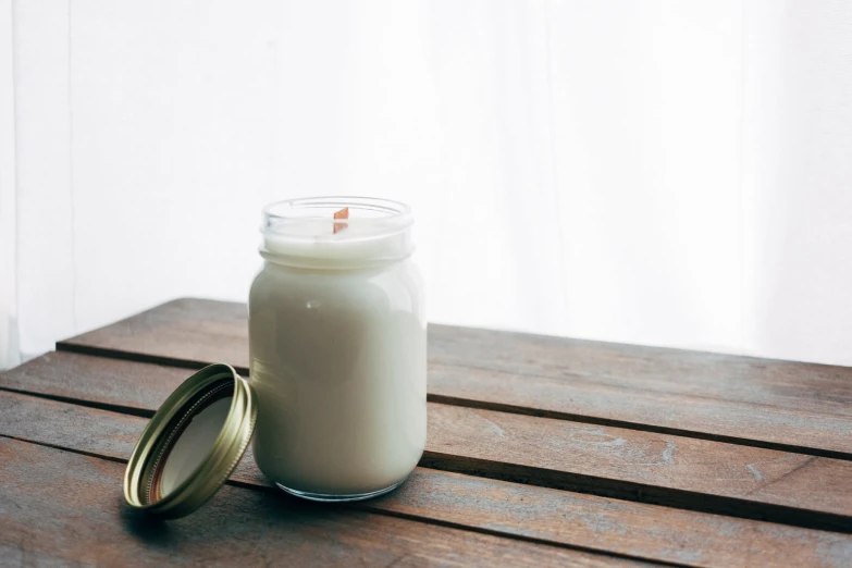 a jar sitting on a wooden table next to a candle