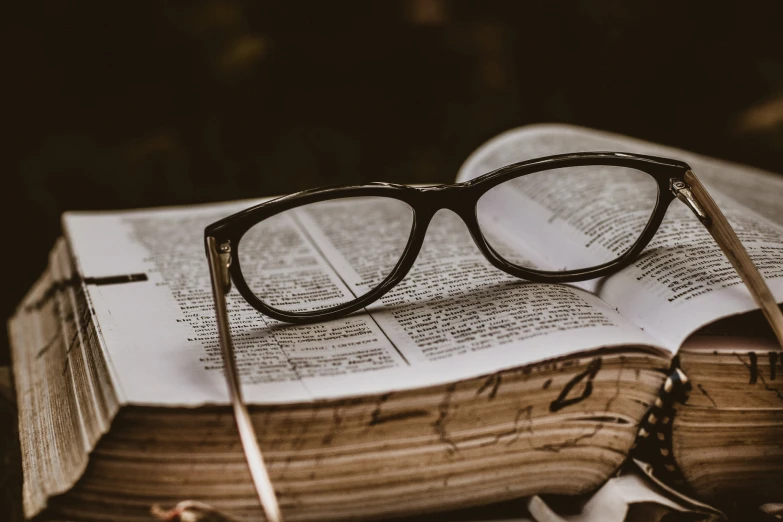 an open book with glasses resting on top of it