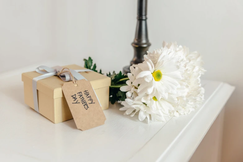 a vase with flowers and paper tags with some gifts