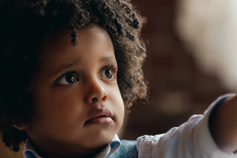 the little boy is wearing a tie and has curly hair