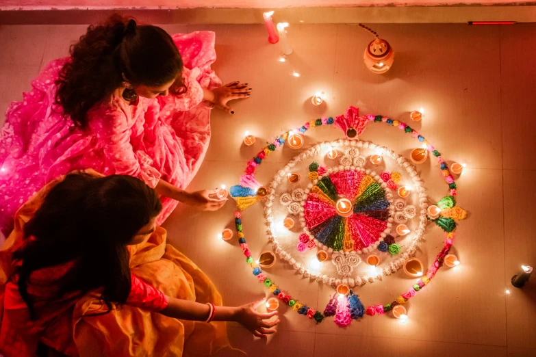 two girls looking at a lighted rangdi on a wall