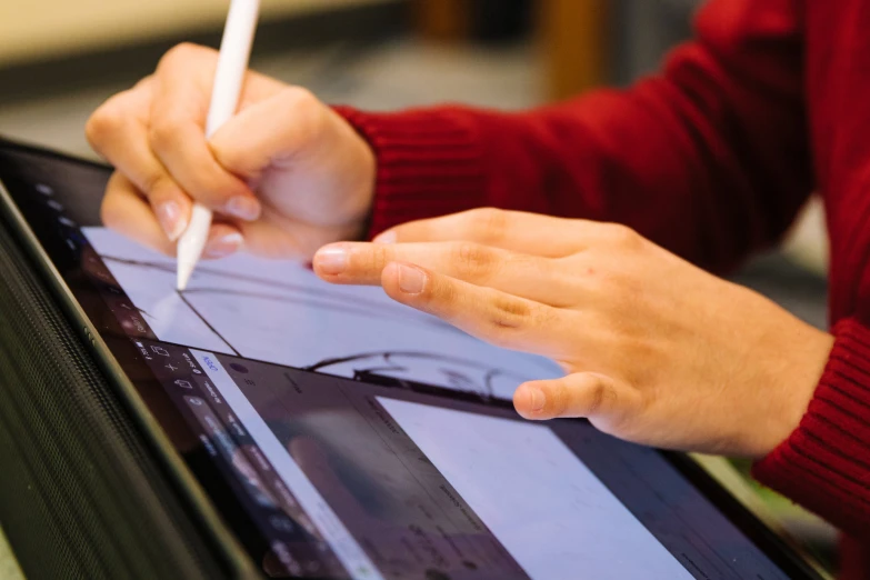 a person writing on an electronic tablet using a pen