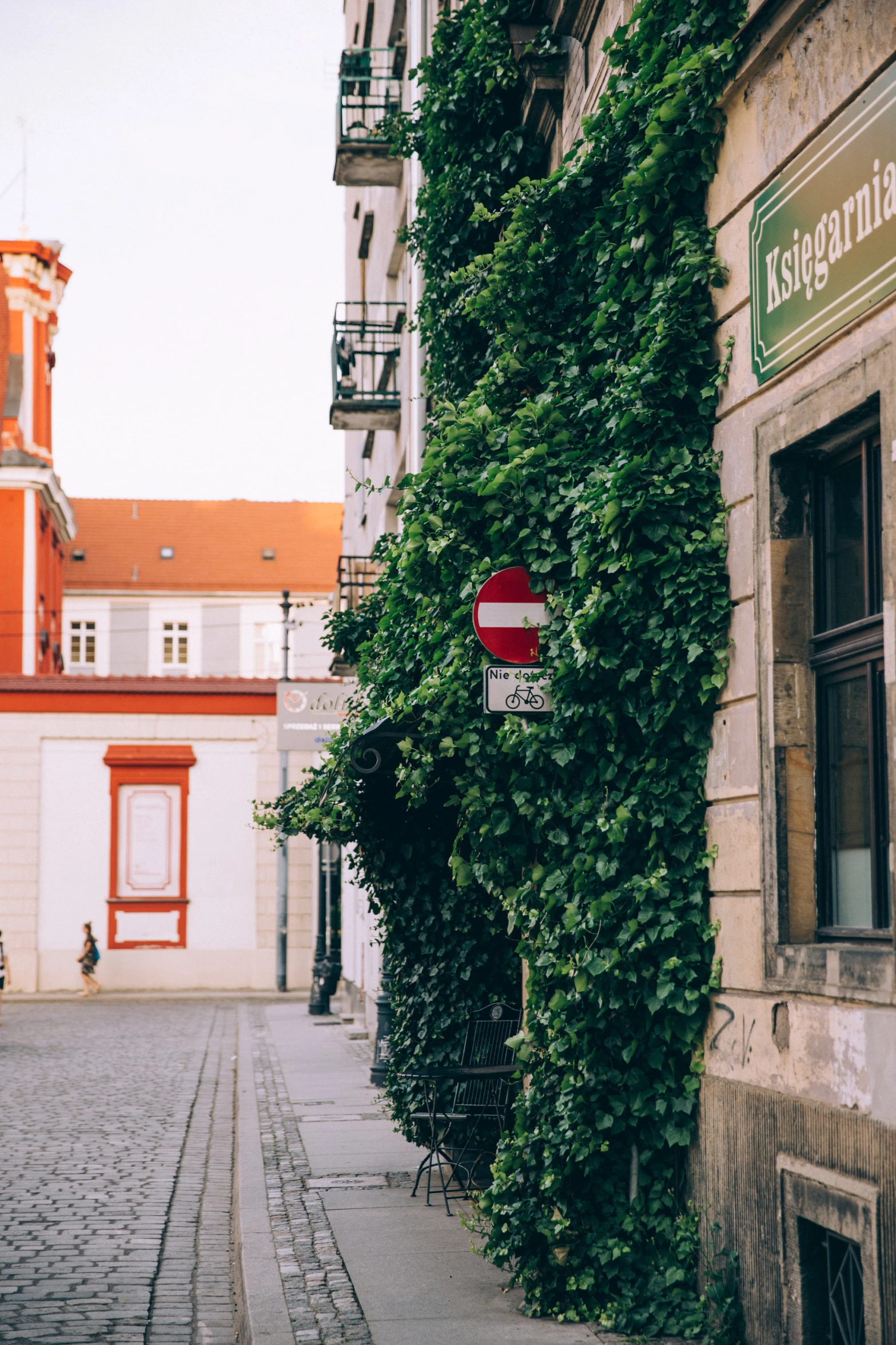 a street sign next to a building covered in greenery