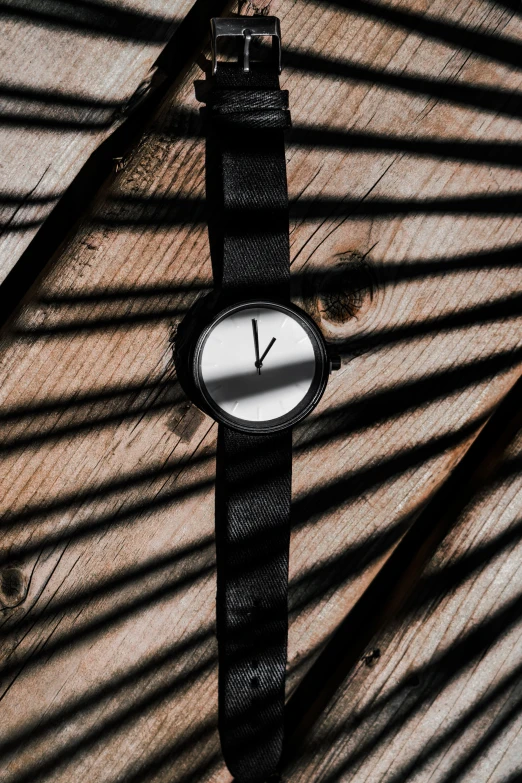 a black and white watch sitting on a wooden table