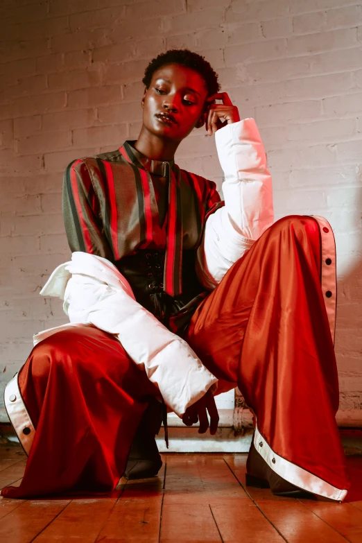 a girl in red is sitting down wearing a striped outfit