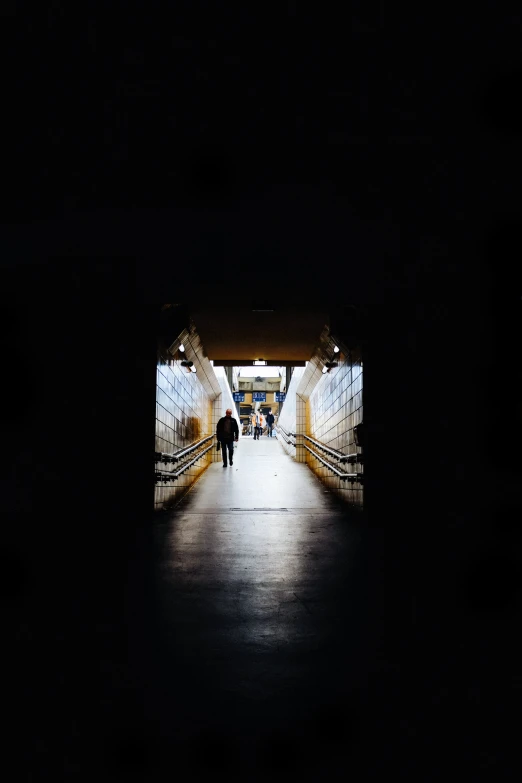 two people walk into the dark tunnel from a walkway