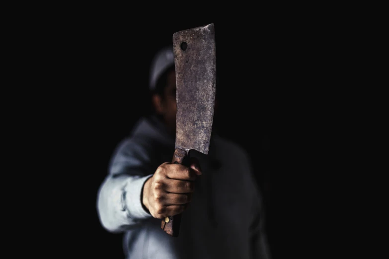 someone holding an old, rusty knife in the dark