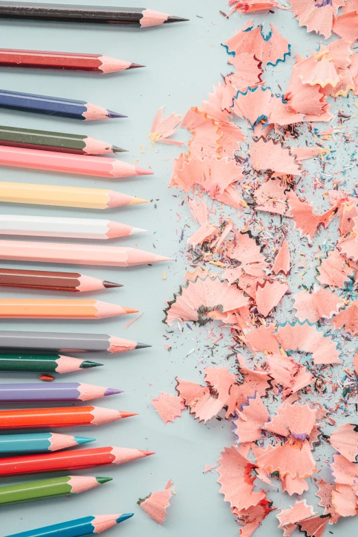 pastel pencils scattered on a blue surface, with the one being colored