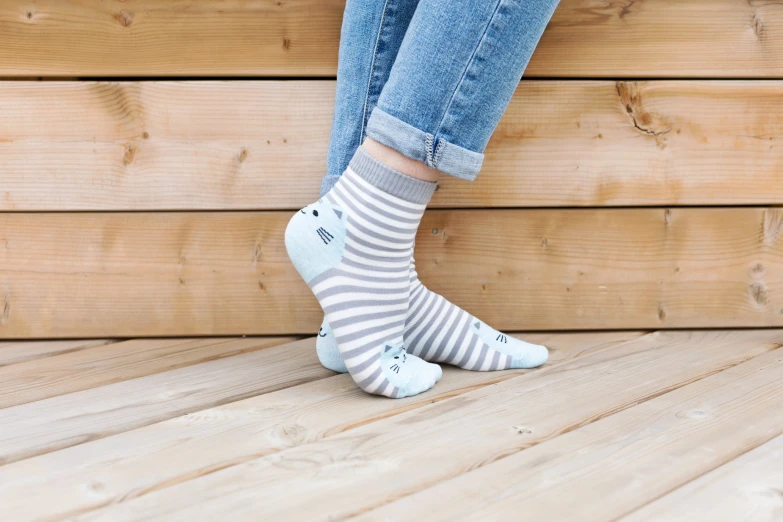 legs of a person wearing blue jeans and a pair of striped socks