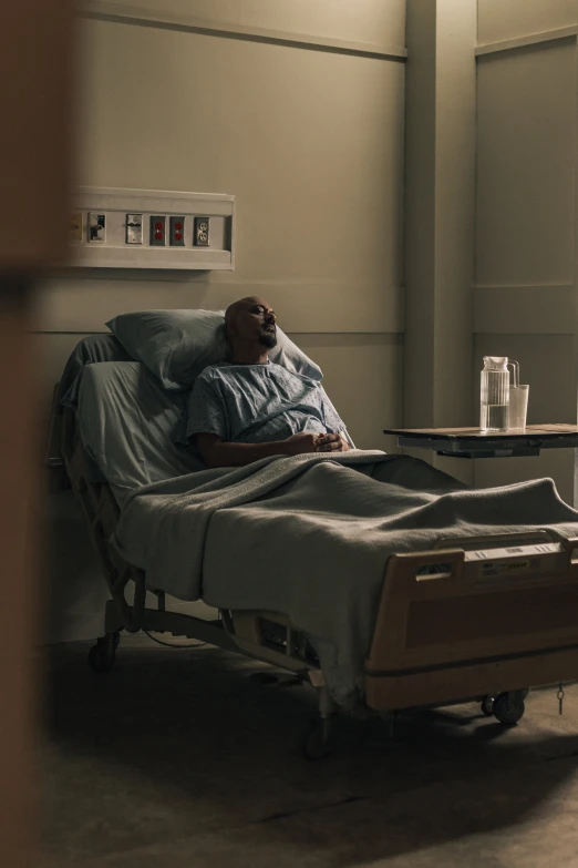 a man in a hospital bed with a glass of water