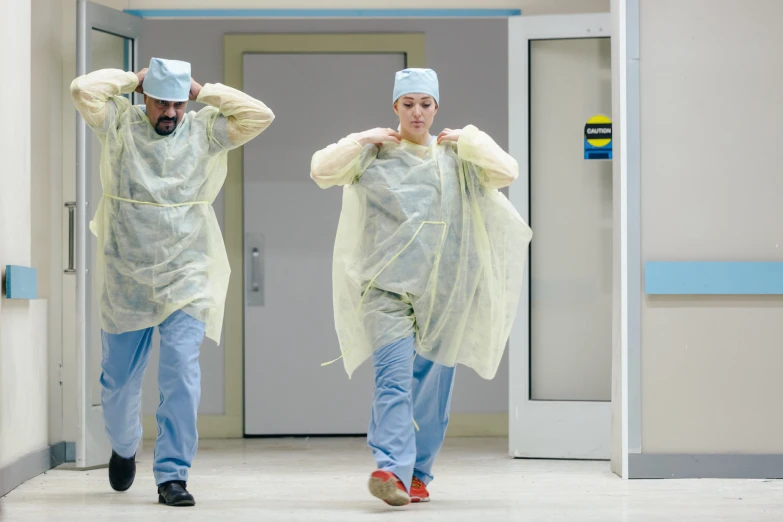 two people with scrubs are running down the hall