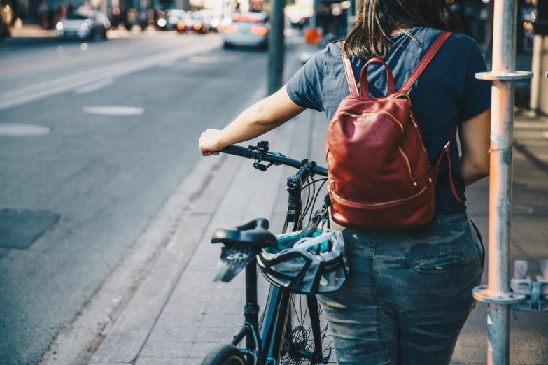 a person on the sidewalk is walking with a backpack and a bicycle