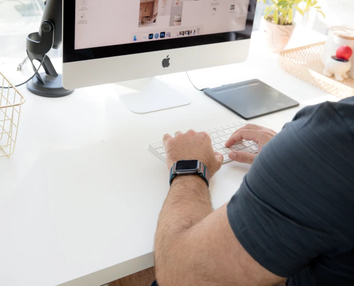 a man is sitting at the computer and looking at his iphone