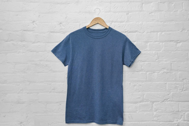 a t - shirt hanging on the wall, with an aged white brick wall behind it