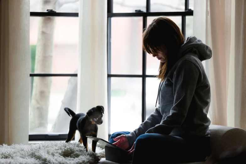  in grey hoodie playing with her pet chihuahua