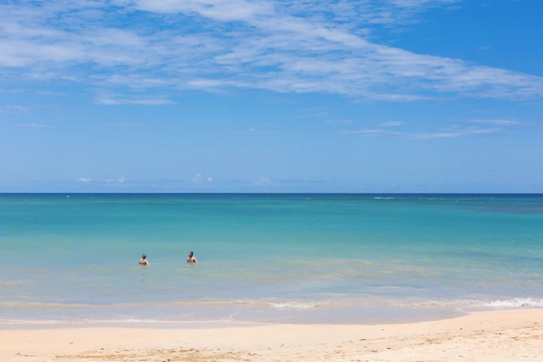 two people in the ocean walking on sand