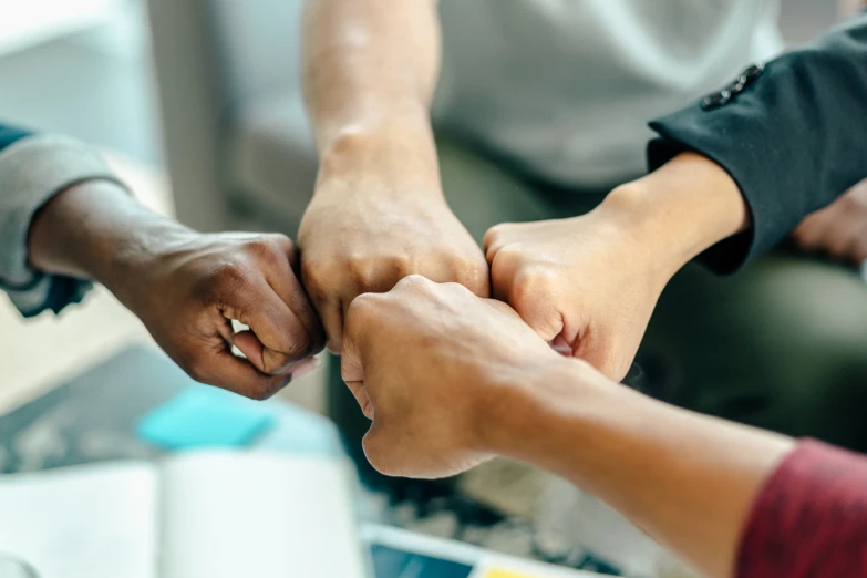 several people holding hands together while sitting in a circle