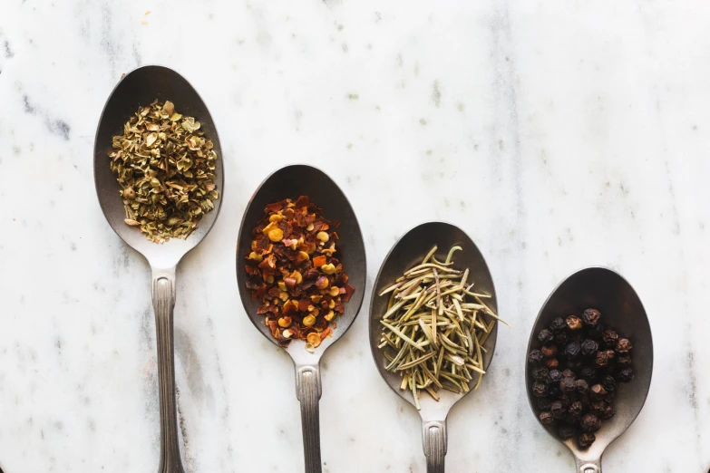 spoons full of spices set against marble table