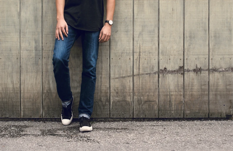 the young man is leaning against the wall in his black shirt