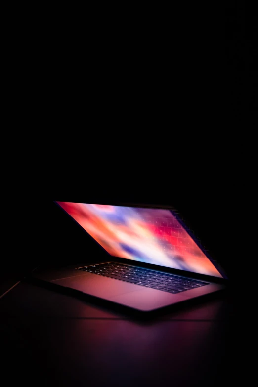 a laptop sits illuminated in the dark by a key pad