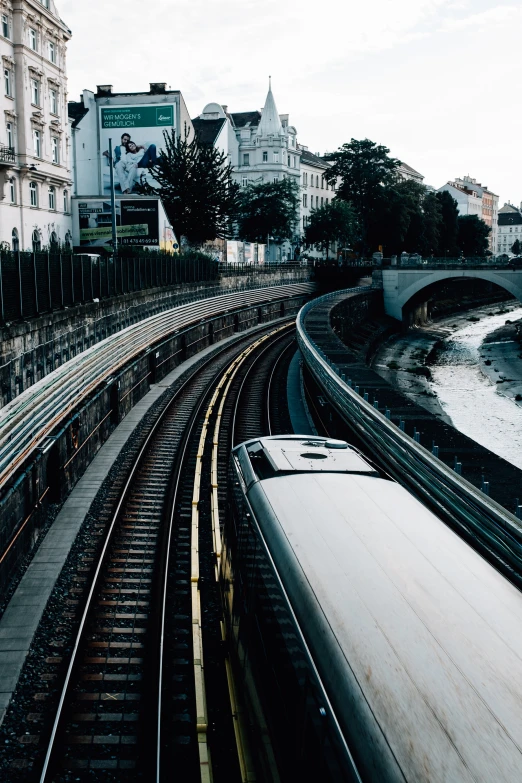 a view of a train moving past buildings and a bridge